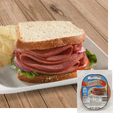 A Halal Beef salami sandwich with white bread red onion, tomato, and lettuce on a white plate with some potato chips behind to the left. A pack of Midamar Halal Classic Salami is overlayed in the bottom right corner. 