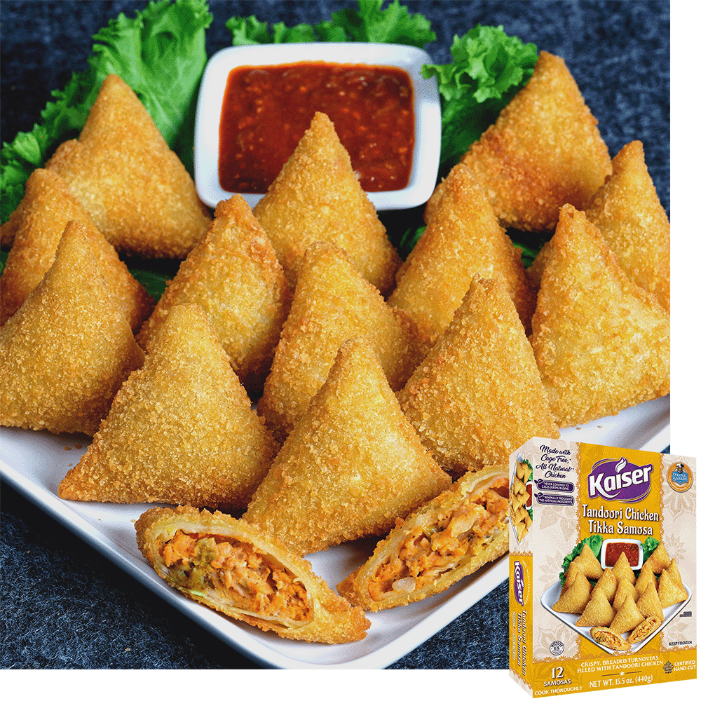 A white plate with 14 breaded chicken samosas arranged in line with one samosa cut open in the from exposing a minced chicken stuffing. a bed of lettuce in the back with a bowl of chili paste on it. A package of Kaiser Tandoori Chicken Tikka Samosas is overlaid in the bottom right corner.