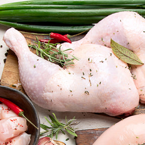Raw chicken with herbs and spices on a wooden cutting board