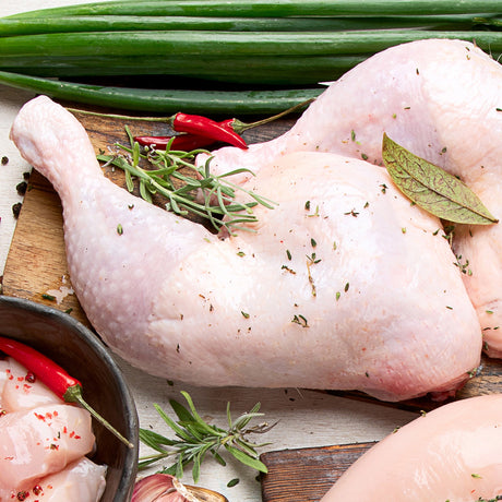 Raw chicken with herbs and spices on a wooden cutting board